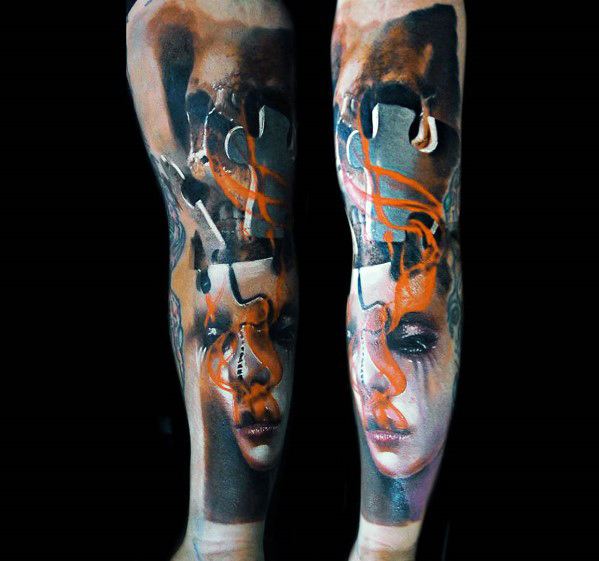 Surreal leg tattoo featuring dual female faces, abstract shapes, and flowing orange lines, creating a dreamlike and emotional composition.