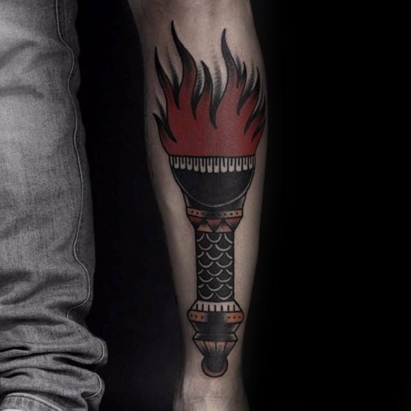 Classic torch tattoo with bold black outlines, red and black flames, and a handle featuring scale-like and geometric patterns.