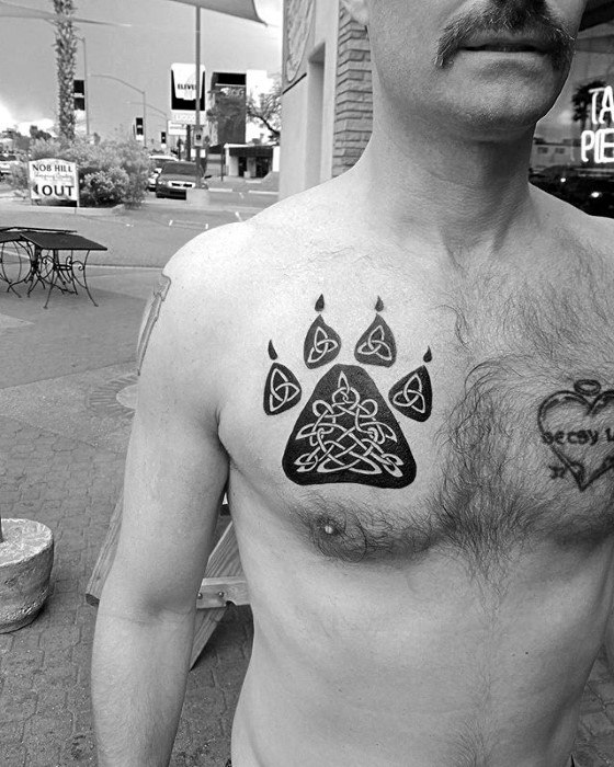 Celtic wolf paw tattoo on chest with bold black outline, featuring five intricate triquetra symbols in each pad and claw.