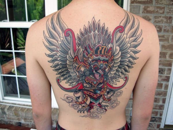 Colorful Garuda tattoo on the back featuring a winged mythical figure with bold red, grey, and gold accents standing over clouds.