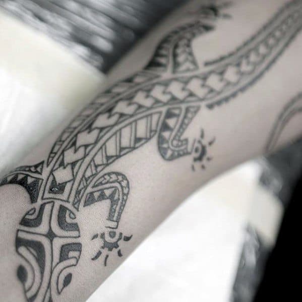 Tribal gecko tattoo with fine black linework and geometric details, stretching along the forearm in a sleek, flowing design.