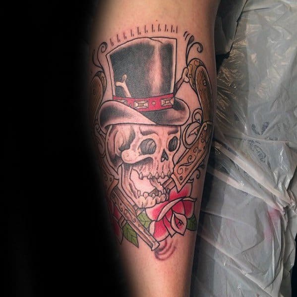 Tattoo of a skull in a top hat with a red band, detailed revolvers, and a blooming rose, blending vintage and Guns N' Roses themes.