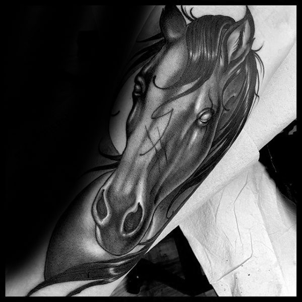 Black and grey tattoo of a horse's head with flowing mane and soft shading, placed on the forearm for a bold yet graceful look