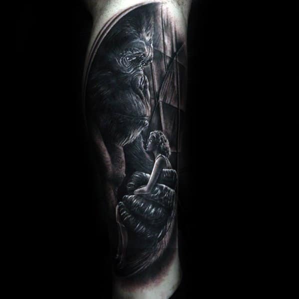 Black and grey King Kong tattoo capturing an emotional moment as Kong gently holds and gazes at a woman in his hand.