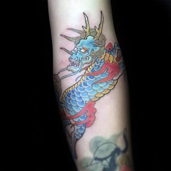 Soft-colored Kirin tattoo on the forearm with pastel blue and yellow scales, red flames, and gentle linework in a delicate traditional style.