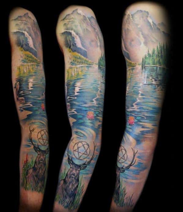 Full sleeve tattoo featuring a serene lake with mountain reflections, a deer with a dreamcatcher, pine trees, and soft pink water lilies.