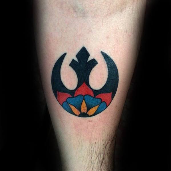 Rebel Alliance tattoo on the forearm, featuring a colorful floral design at the base in red, blue, and yellow