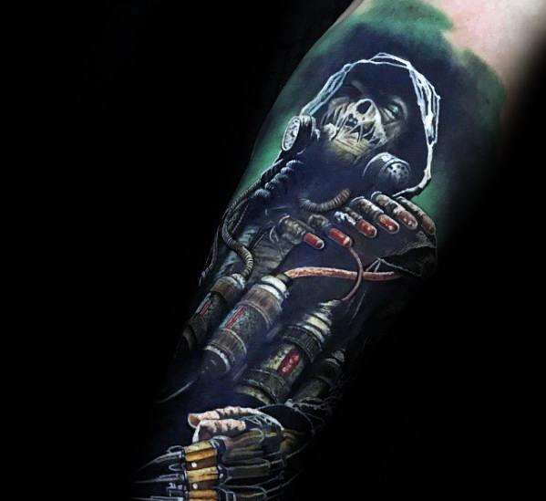 Vibrant scarecrow tattoo with a skull-like face, gas mask, hood, glowing green background, and wires connected to syringe-filled gloves.