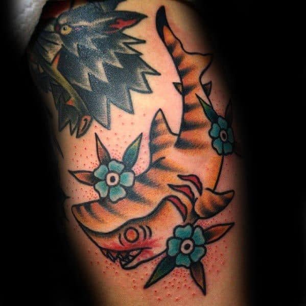 Traditional tiger shark tattoo with orange stripes, red gills, and playful blue flowers, blending bold lines with a touch of whimsy.
