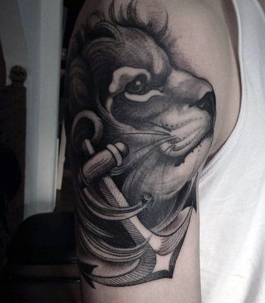 Tattoo of a lion's face with an anchor on an upper arm in grayscale