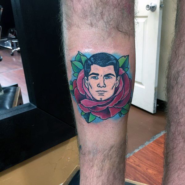 Archer tattoo featuring his face emerging from a bold, vibrant red rose with green leaves, blending classic and modern tattoo styles.