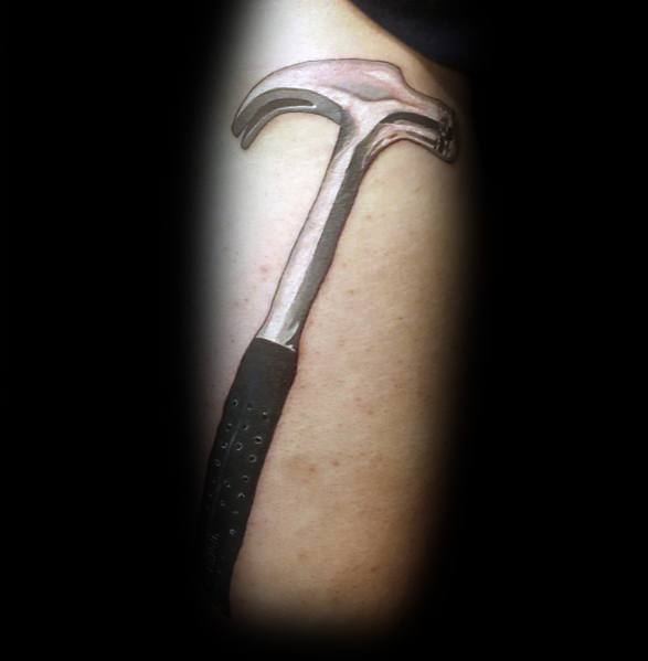 Realistic black and gray tattoo of a claw hammer on the arm, symbolizing strength, craftsmanship, and dedication to hard work and building.