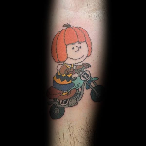 Playful Charlie Brown tattoo featuring him riding a mini bike with a pumpkin helmet, blending Peanuts nostalgia with a fun Halloween twist.
