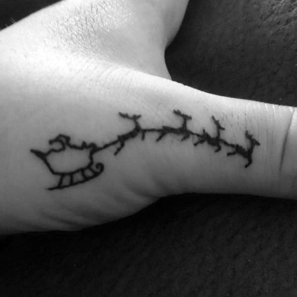 Minimalist Christmas tattoo of Santa’s sleigh being pulled by reindeer, inked in a simple black outline on the wrist for a subtle festive touch.