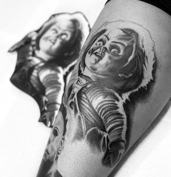 Black and grey Chucky tattoo with intense shading, featuring his eerie grin, glowing highlights, and a haunting horror-inspired design.