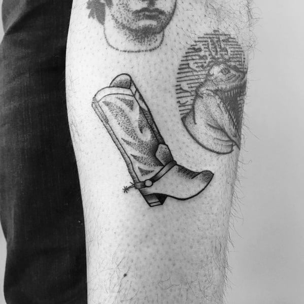 Minimalist black and white tattoo of a cowboy boot with a spur, featuring fine details and a sleek design, symbolizing Western culture and style.