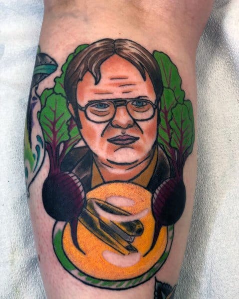 Colorful tattoo of Dwight Schrute with a serious expression, surrounded by beets, featuring a stapler encased in Jell-O at the bottom.