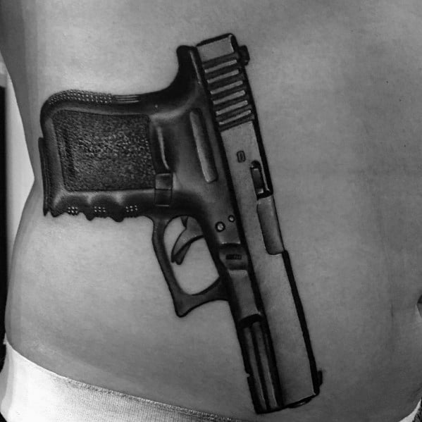 Realistic black and grey tattoo of a Glock pistol on the waist, featuring detailed shading and depth for a bold and three-dimensional effect.