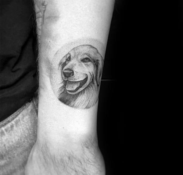 Small realistic Golden Retriever tattoo on the wrist, featuring fine-line shading and a circular frame, capturing a joyful expression in detail.