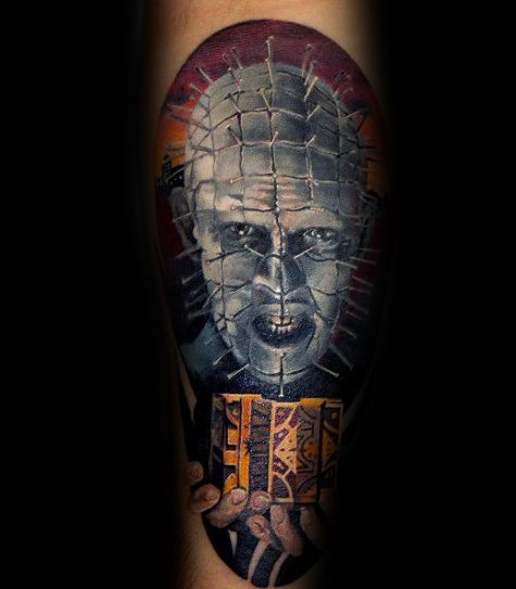 Color *Hellraiser* tattoo of Pinhead holding the Lament Configuration, featuring eerie shading, realistic pin details, and a dark, ominous background.