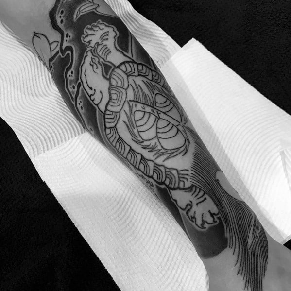 Black and grey Japanese-style forearm tattoo featuring a swimming turtle with flowing water elements, symbolizing strength, wisdom, and perseverance.