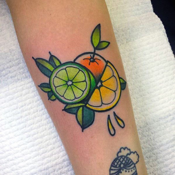 Bold citrus tattoo featuring a lime and orange with vibrant green and yellow shading, detailed leaves, and juice droplets for a fresh design.