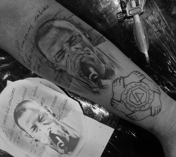 Black and gray tattoo of Chester Bennington singing, with handwritten lyrics and a unity symbol featuring the Linkin Park logo on the wrist.