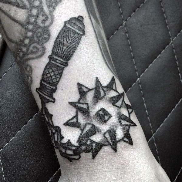 Bold black ink mace tattoo featuring a spiked ball on a chain with a detailed handle, symbolizing strength, power, and medieval warfare.