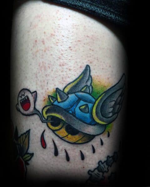 Mario-themed tattoo featuring a spiked blue shell with wings and a playful Boo, inked in bold colors with shading and dynamic details.