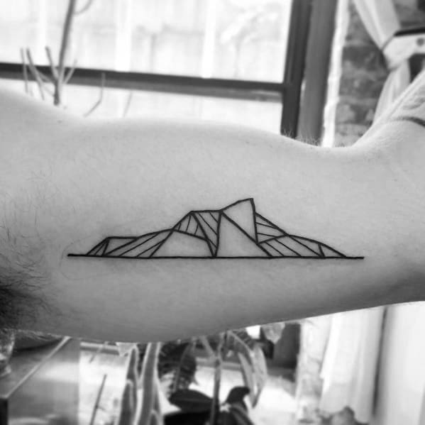 Minimalist geometric mountain tattoo on the inner arm, featuring clean lines and angular shapes with a continuous horizontal base for a modern look.