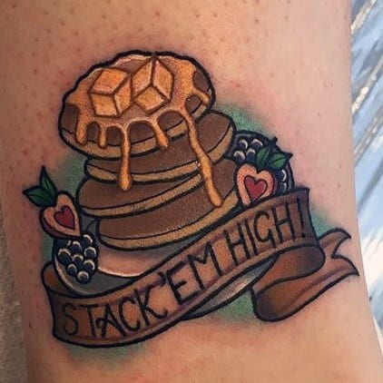 Pancake tattoo with syrup, butter, berries, and a banner reading "Stack 'Em High!" featuring bold outlines and a classic vintage style.