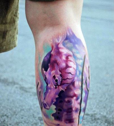 Watercolor seahorse tattoo on calf, featuring soft purple and blue hues with a fluid, artistic design for a dreamy and vibrant oceanic look.