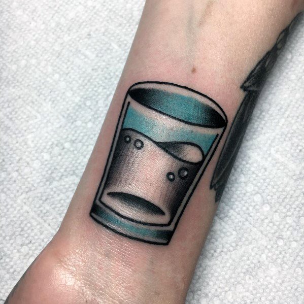 Minimalist shot glass tattoo with a bold black outline, blue shading, and bubbles inside, creating a sleek and modern design on the wrist.