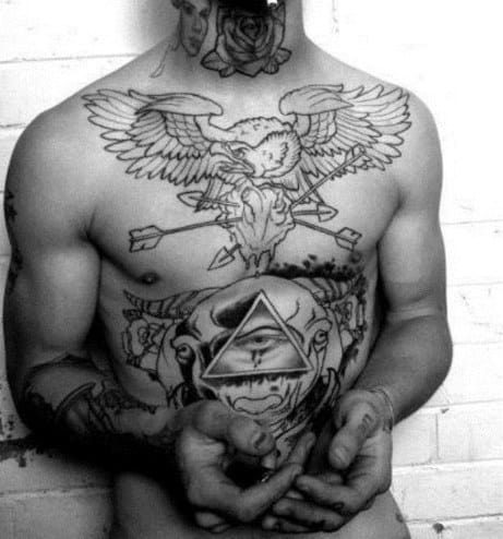 Man with eagle and geometric shapes tattooed on chest holding hands together