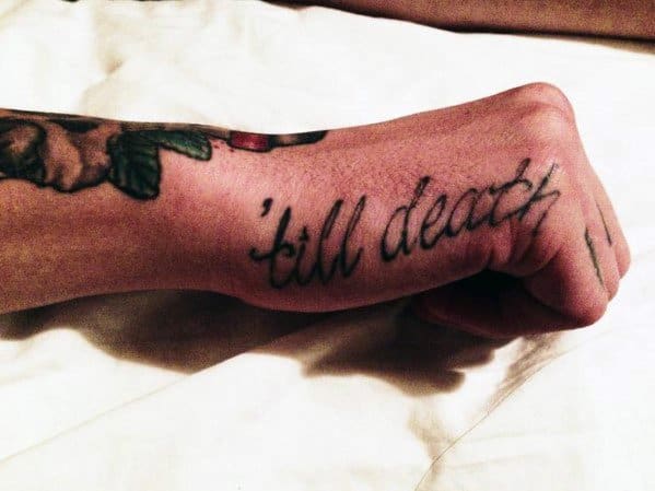 Side hand tattoo for men with the phrase 'till death' in a loose, handwritten script inked along the edge of the hand.