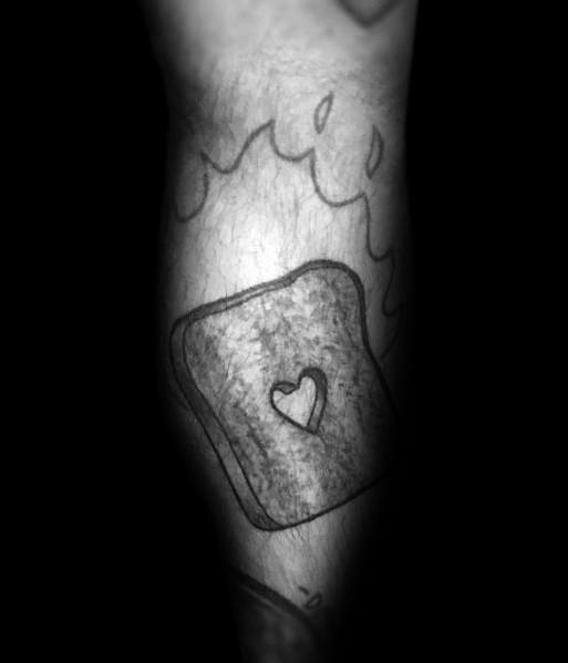 Simple black ink toast tattoo with a small heart-shaped cutout in the center, featuring soft shading for a minimalist and sentimental design.