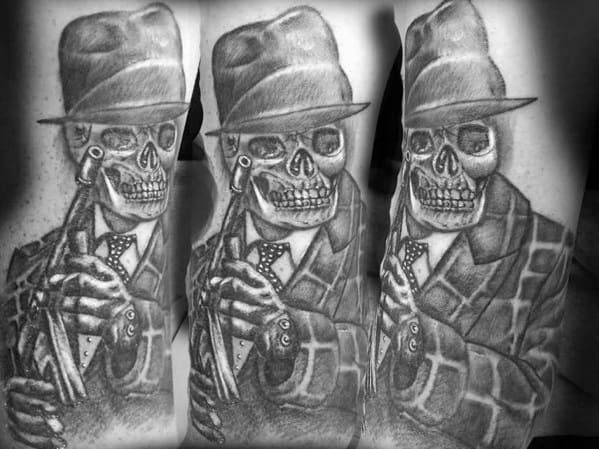 Black and grey tattoo of a skeleton gangster in a fedora and suit holding a Tommy gun, featuring detailed shading for a bold vintage crime theme.