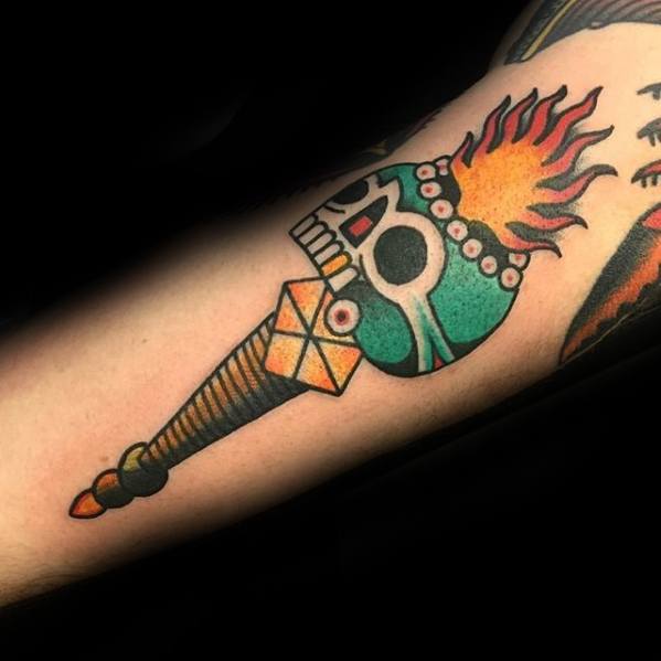 Colorful torch tattoo with a turquoise skull-shaped flame holder, vibrant fire, and a bold, geometric handle design.