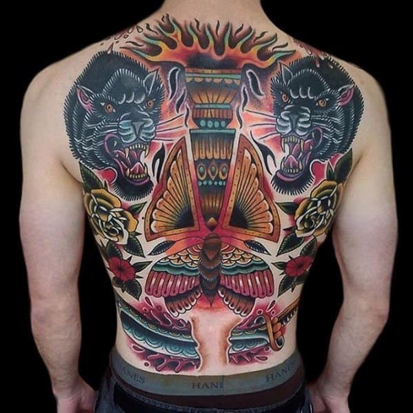 Full back tattoo featuring a large central torch with fiery flames, flanked by two fierce panthers, roses, and a detailed moth at the base.