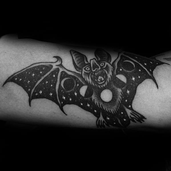 Black and grey bat tattoo with starry wings and moon phases across the body, blending cosmic and traditional styles.