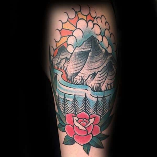 Traditional tattoo with a flowing river, pine trees, and towering mountains under a cloud-filled sunset sky, accented by a red rose below.