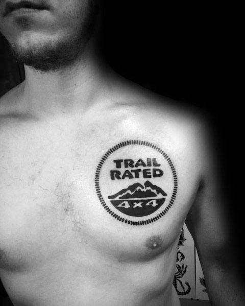 Bold black ink tattoo of the Jeep "Trail Rated 4x4" badge, placed on the chest, symbolizing off-road capability and adventure spirit.