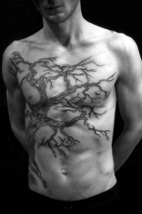 Shirtless man with a detailed tree tattoo covering his chest and abdomen