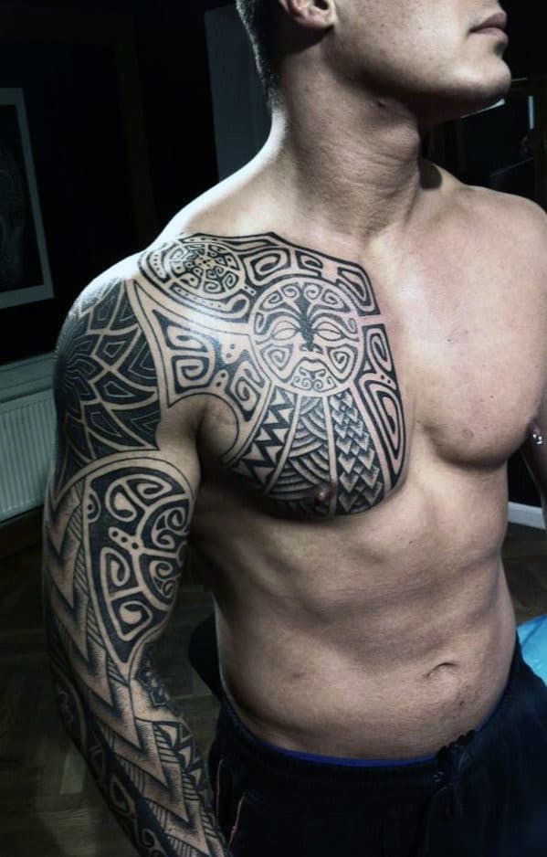 Man with intricate black tattoo covering shoulder, chest, and arm, in a tribal style