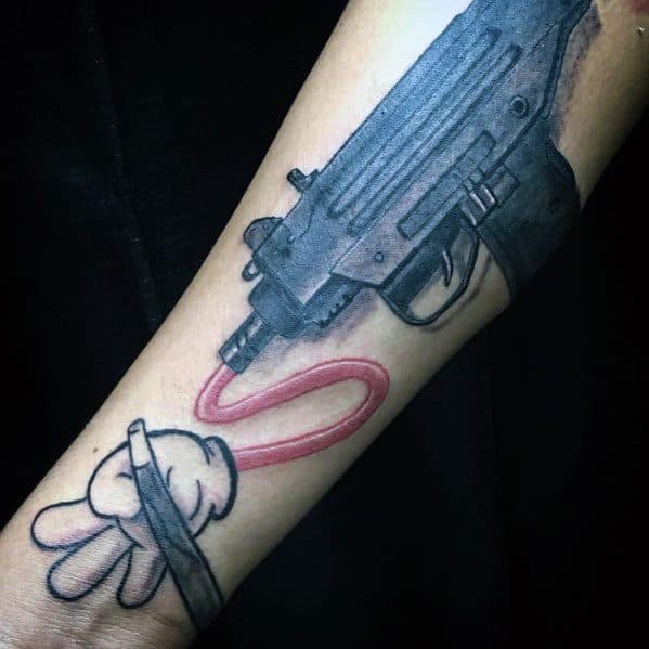 Black and grey Uzi tattoo on the forearm with a cartoon-style hand guiding a red looping cord, blending realism with playful artistic elements.