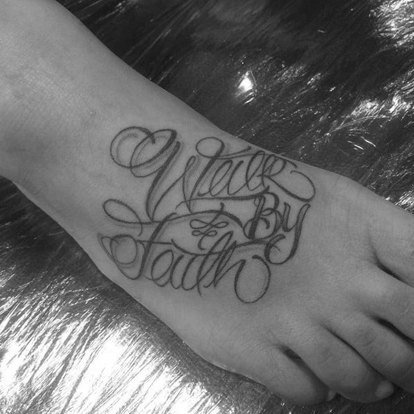 Foot tattoo featuring "Walk by Faith" in an artistic cursive script with bold, flowing lines, creating a striking and inspirational design.
