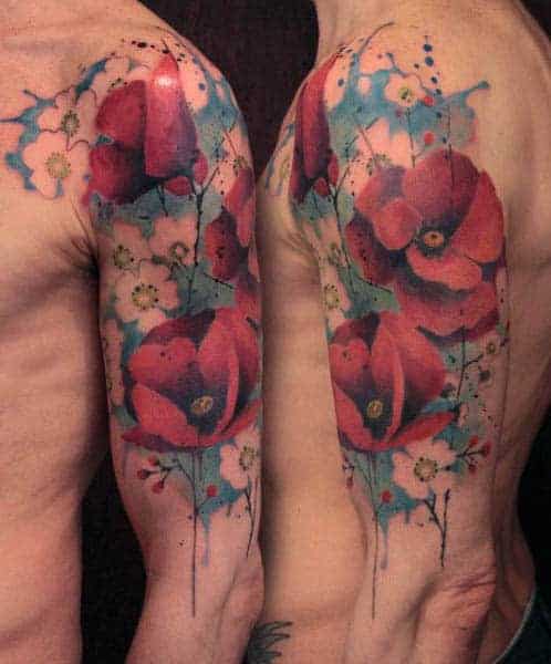 This vibrant watercolor tattoo features bold red poppies with splashes of blue and white accents, creating a dynamic and artistic half-sleeve design