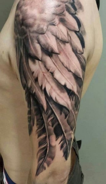 Arm tattoo of realistic feathers in black and grey ink, covering the shoulder and arm