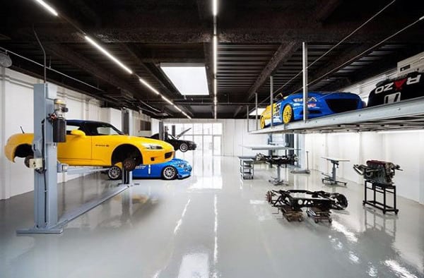 A modern workshop-style garage featuring car lifts, polished floors, and ample workspace.