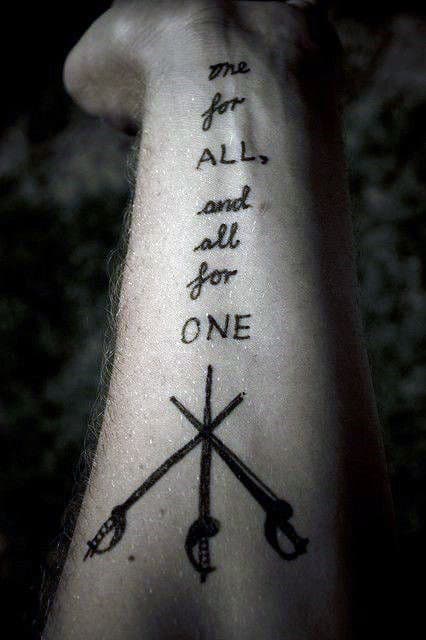 One for all, and all for one" tattoo with swords on a forearm